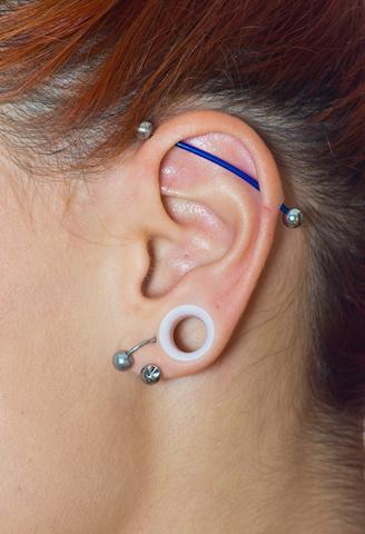 Piercing oben am Ohr: Industrial Piercing mit blauem Stab